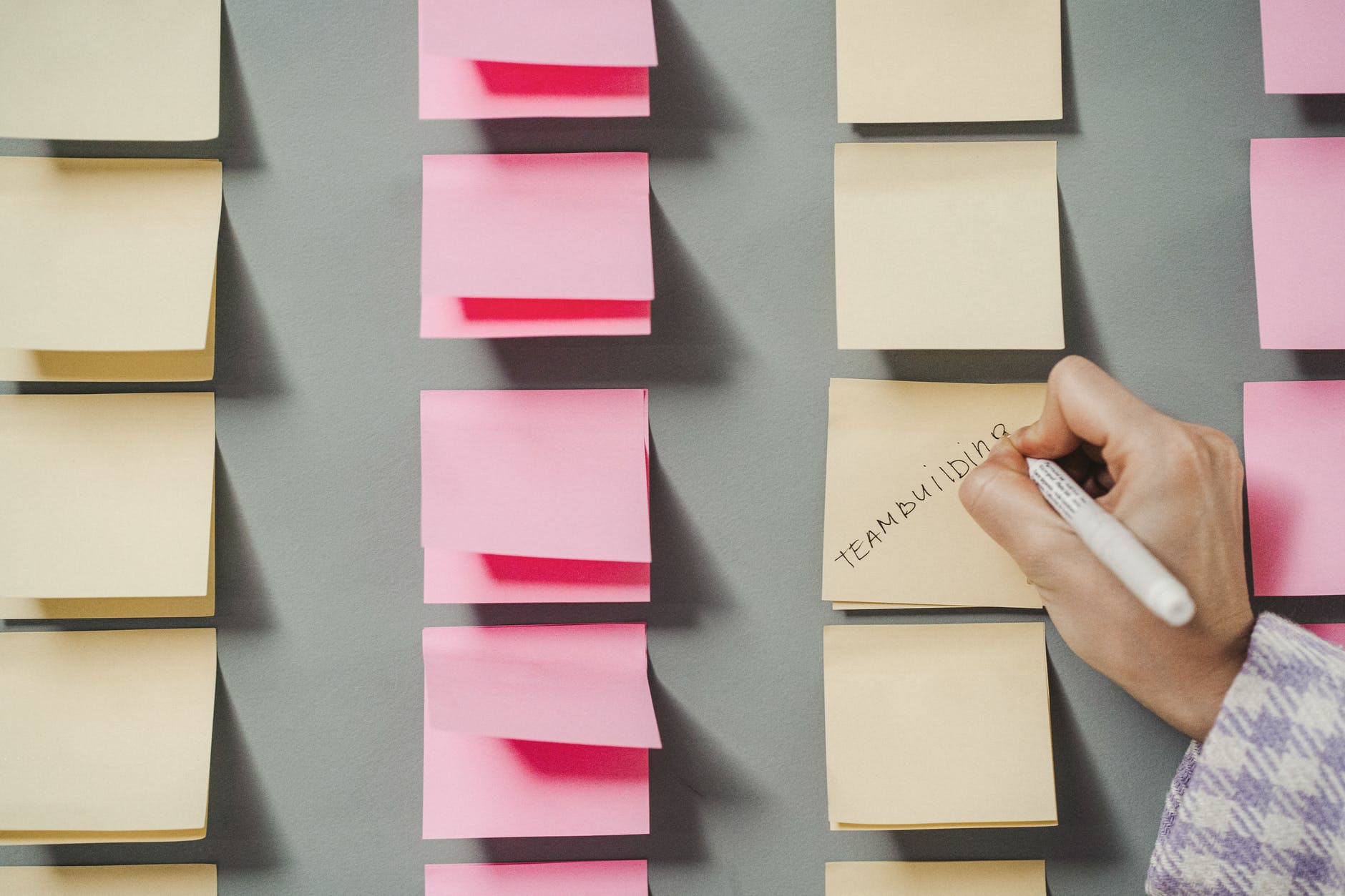person writing on yellow sticky note